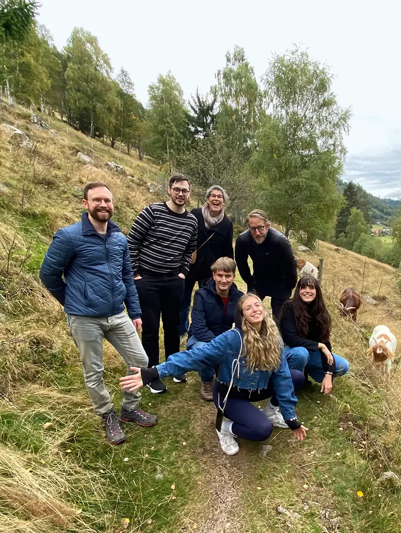 A group photo of the team on a hike, next to some goats