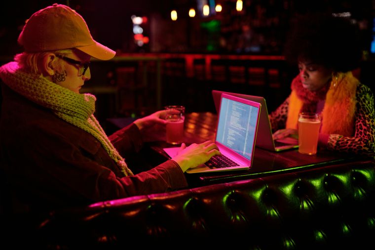 Two people are working on laptop in a bar