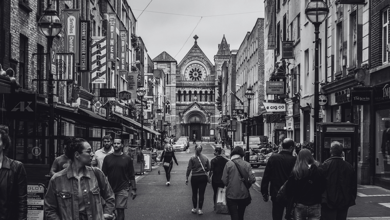 Street scene in Dublin shows people walking toward the striking Neo-Romanesque facade of St. Ann's Church