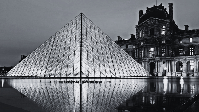 This is a nighttime photo of the illuminated Louvre Pyramid in Paris