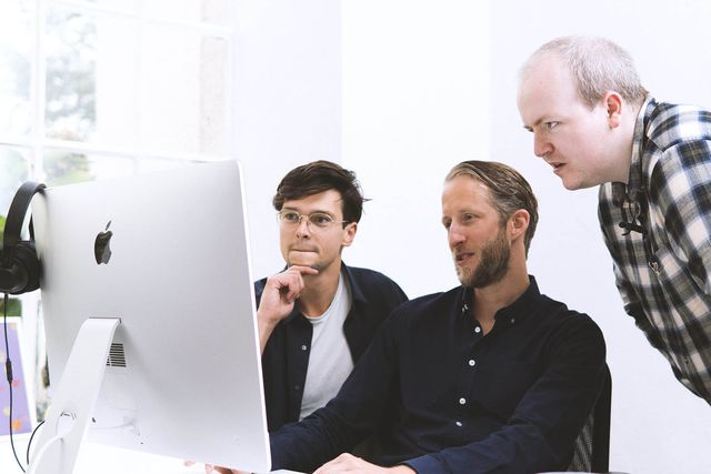 Three team members looking at a computer screen