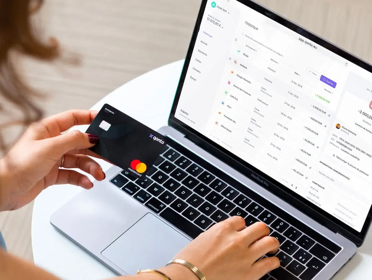 Woman holds a credit card while using the Qonto web application