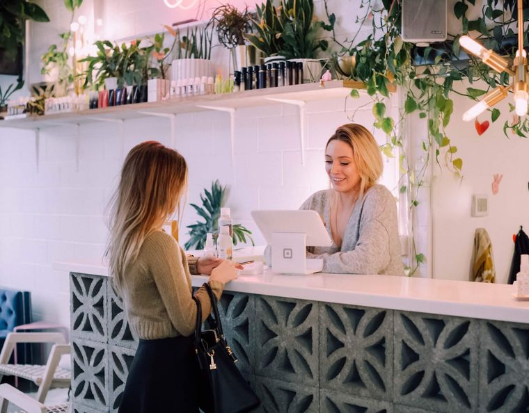 Smiling blonde woman behind a counter serving another woman