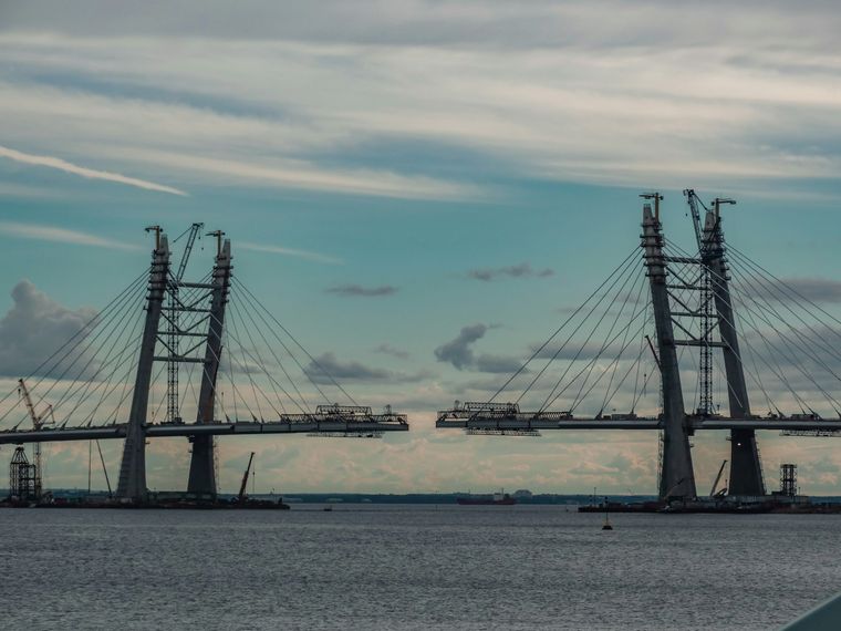 A cable-stayed bridge under construction, with two towers and a gap in the middle where the two halves of the deck have not yet been joined.