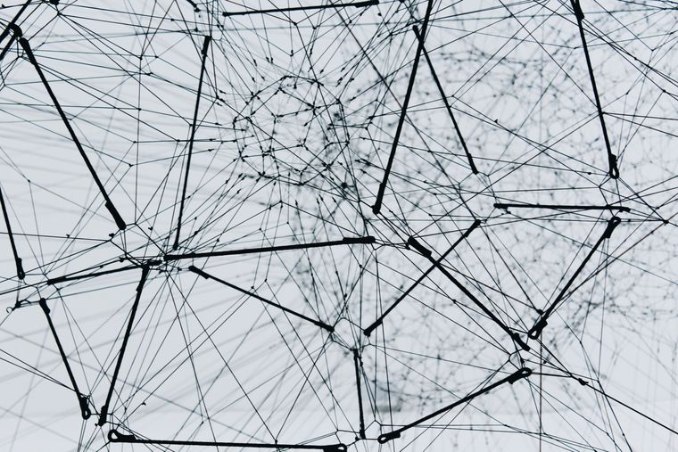A dense, abstract network of thin black lines and nodes forming geometric, web-like connections against a light background.